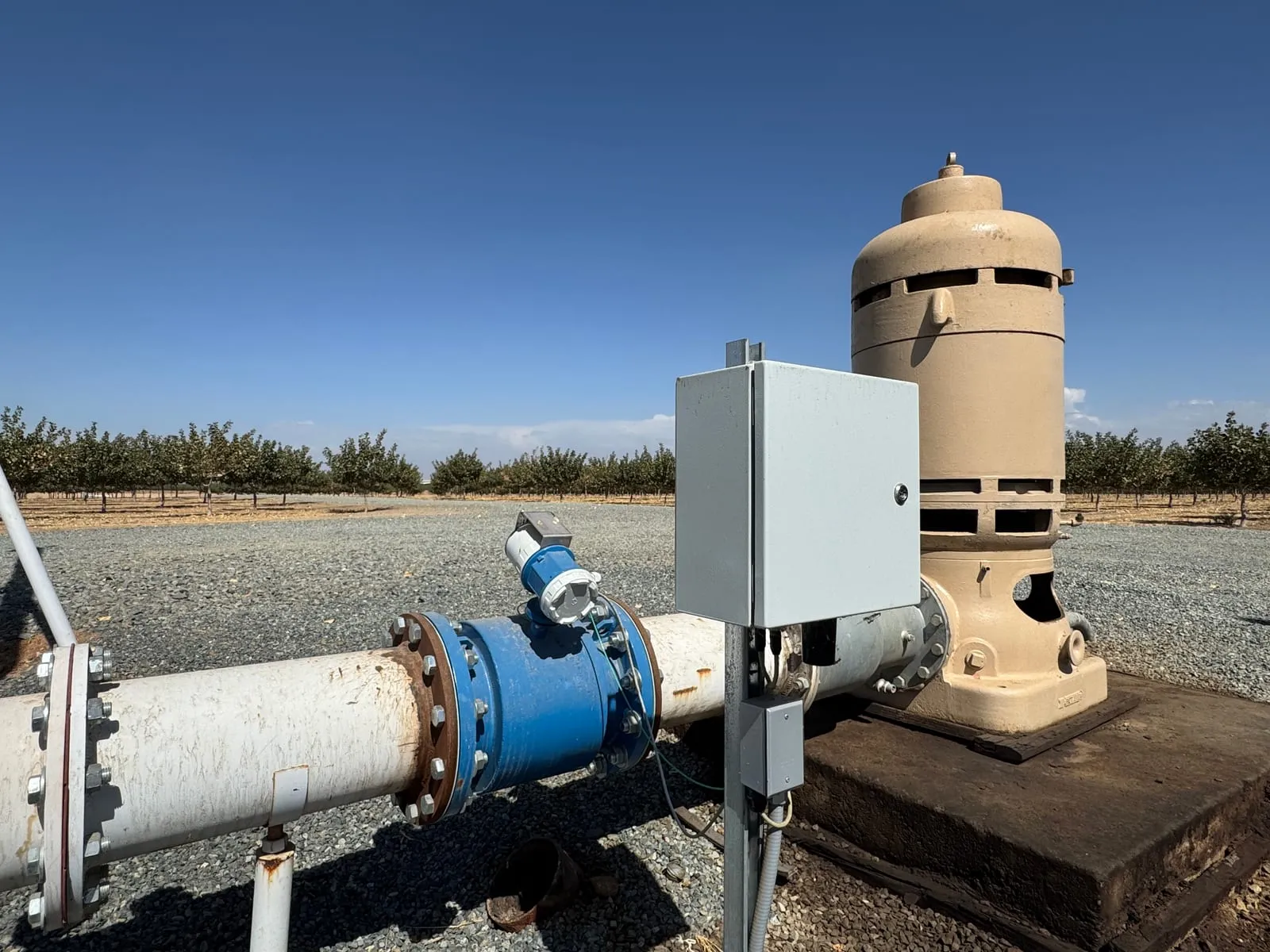 A magnetic flow meter on the discharge line of a vertical well pump motor, with a telemetry enclosure mounted between them